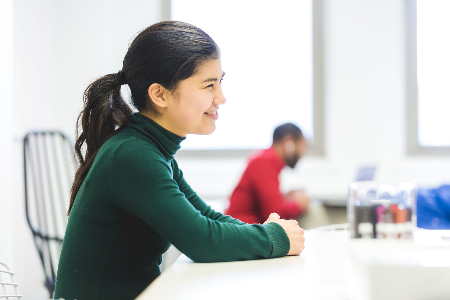 Smiling Woman in an office environment seated at a conference table